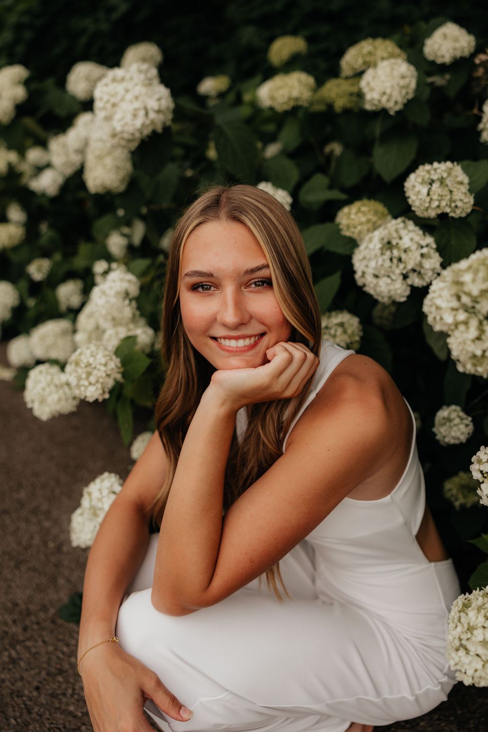 A summer portrait surrounded by blooming white hydrangea flowers in a garden setting.