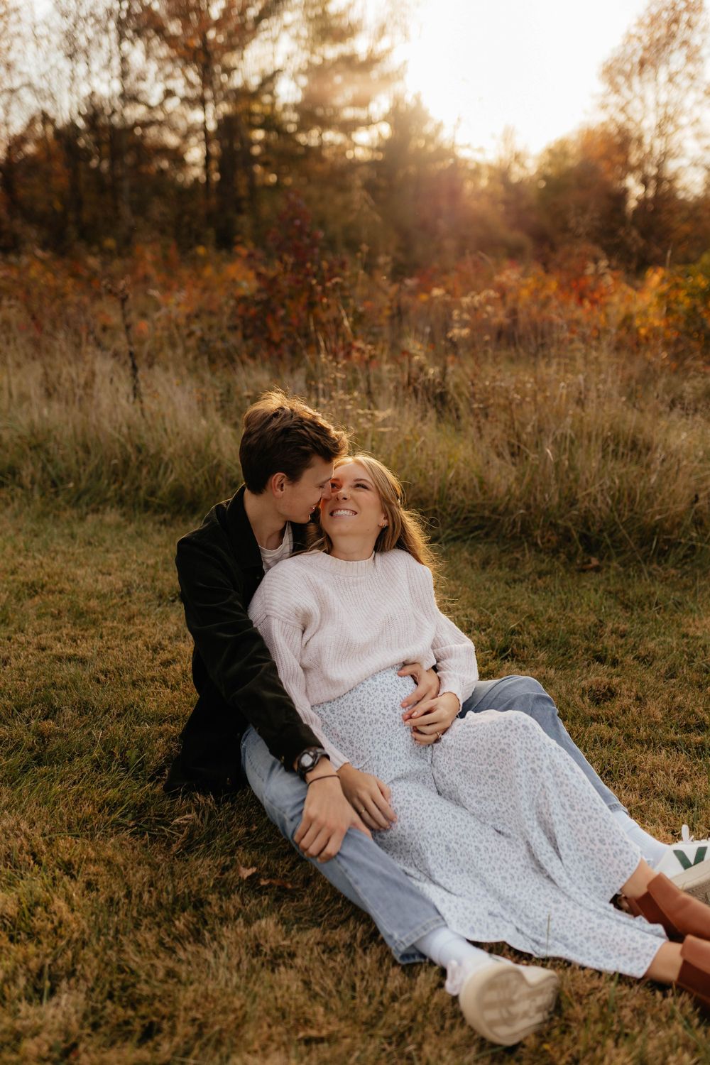 Romantic couple embracing on grass during golden hour sunset.
