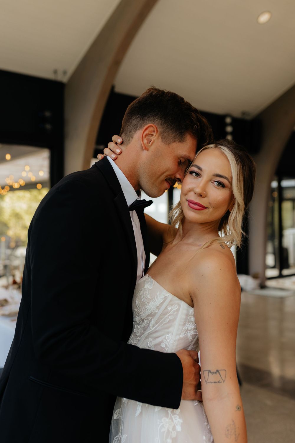 Elegant wedding couple sharing an intimate moment in a modern indoor venue.