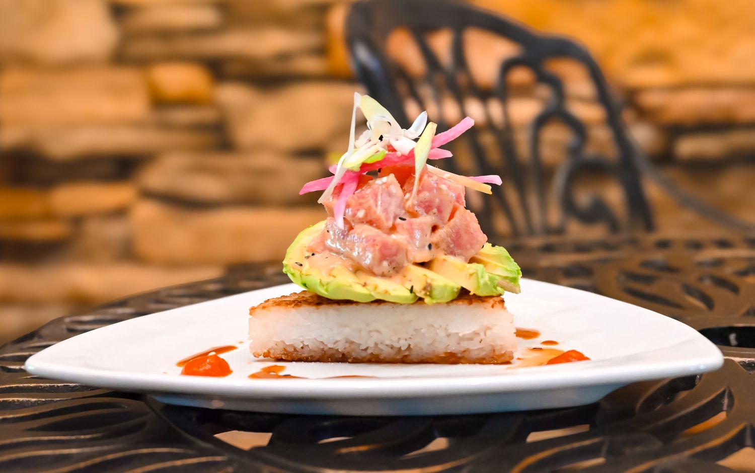 Gourmet tuna dish artfully plated with microgreens and sauce on white porcelain.