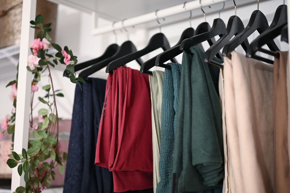 Row of formal dresses hanging on black hangers showing various colors and styles.
