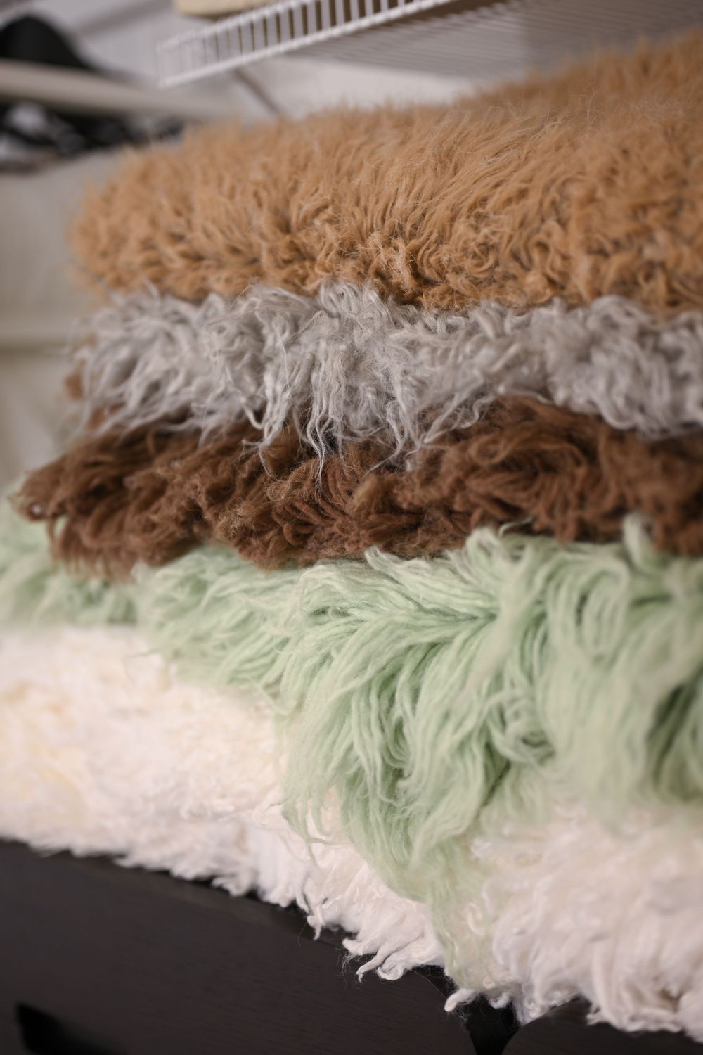 Close-up of layered fabric textures in neutral, mint green and brown tones.