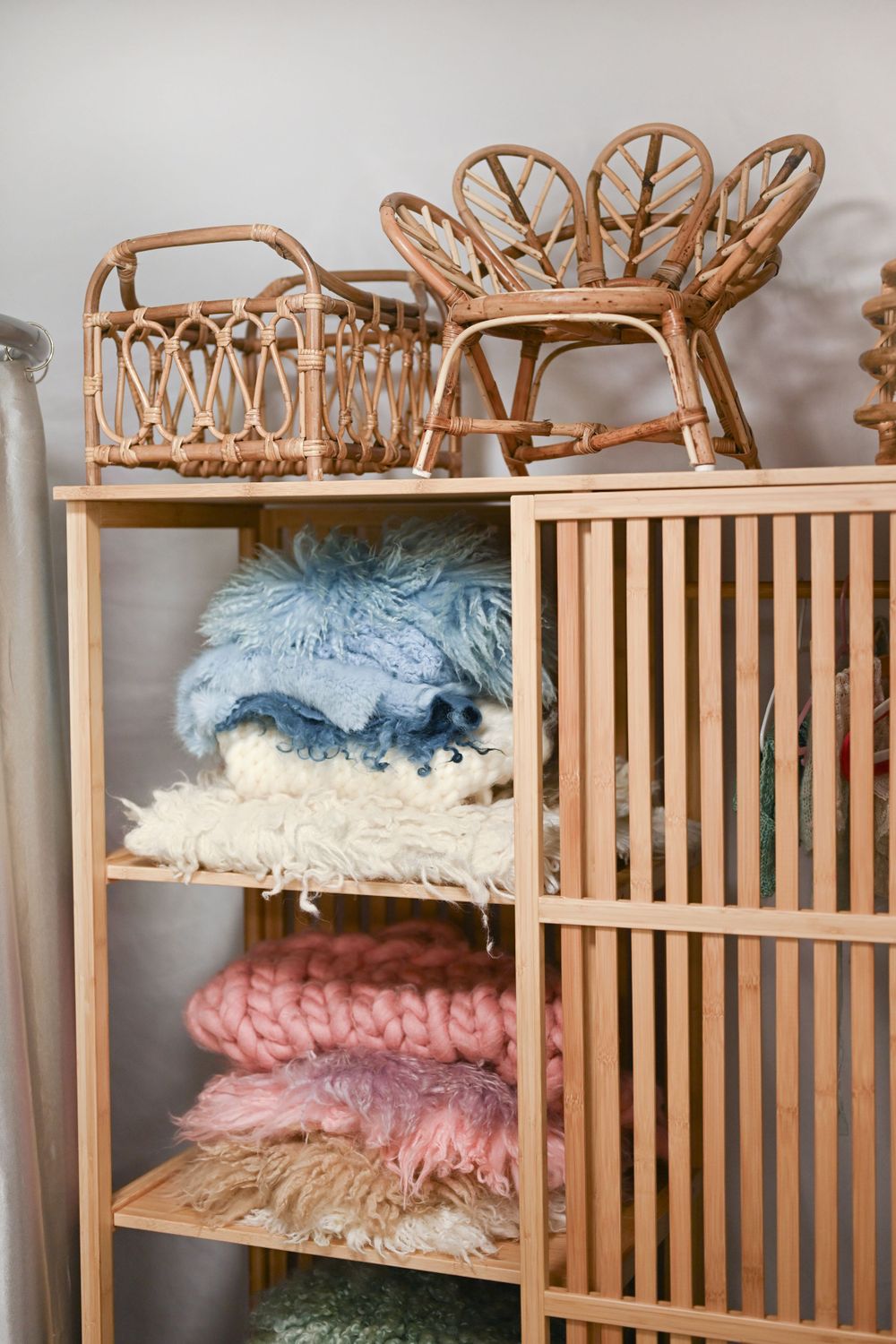 Wooden shelving unit displaying soft textured fabrics and decorative elements.