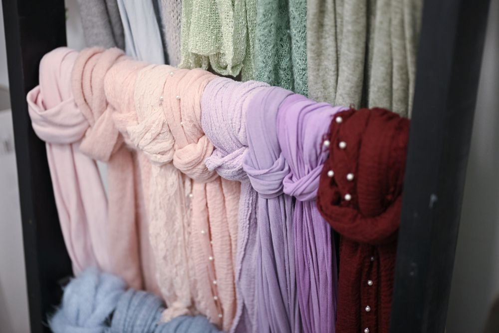 Clothing rack displaying pastel colored dresses in pink, purple and mint green tones.