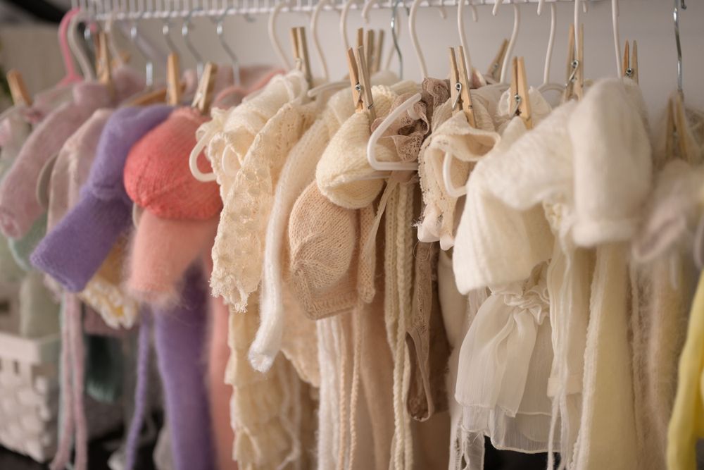 Collection of delicate vintage baby clothes hanging on display.