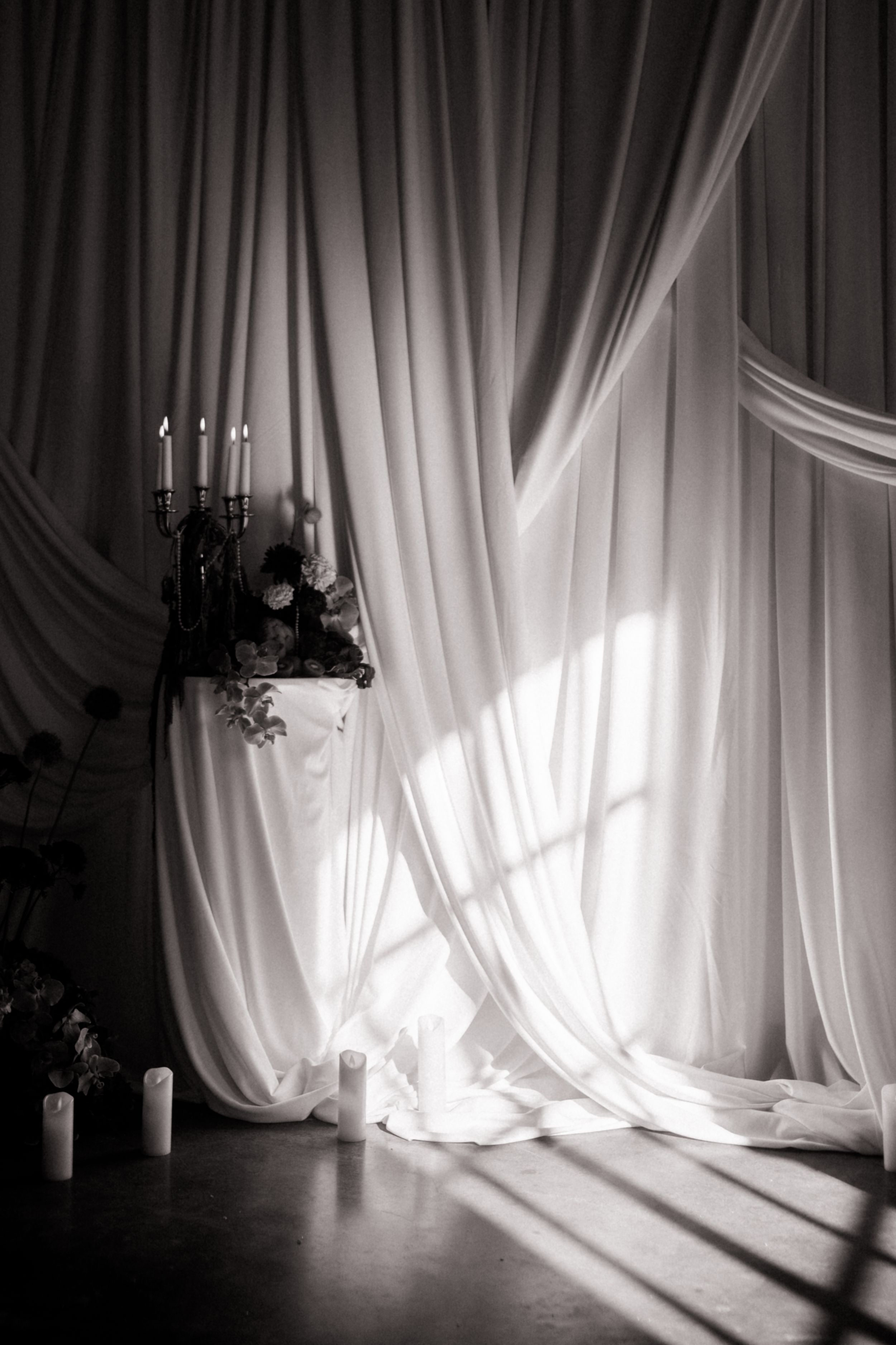 Dramatic black and white photo of flowing curtains with natural light casting shadows.
