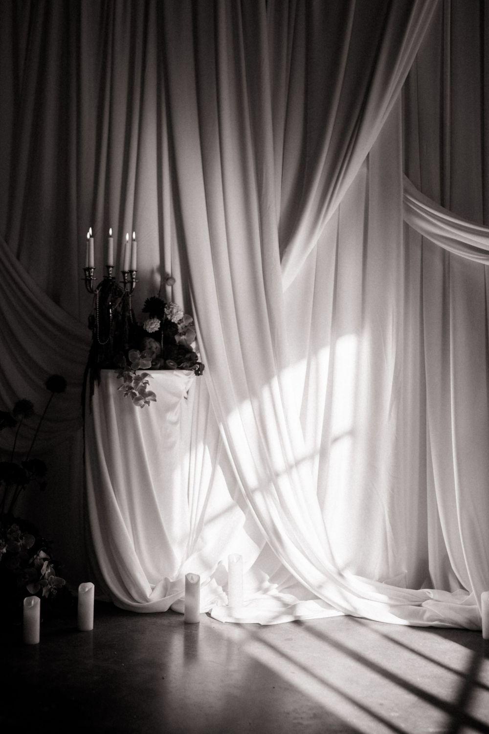 Dramatic black and white photo of flowing curtains with natural light casting shadows.