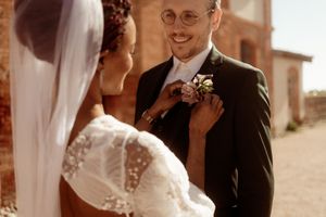 A tender wedding moment captured in warm tones against a rustic brick backdrop.