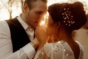 A romantic couple shares an intimate golden hour moment with soft sunlit lighting.