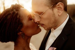 An intimate moment between newlyweds sharing a tender kiss at sunset.