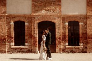 Panoramic view of a rustic brick venue with arched windows and white accents for a wedding ceremony.