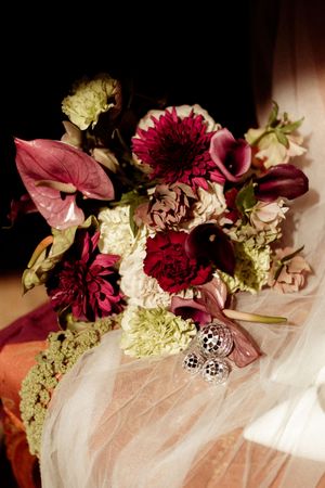 Burgundy and cream floral arrangements with delicate petals displayed on white fabric.