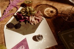 A vintage-style wedding invitation with dried flowers and delicate details on wooden surface.