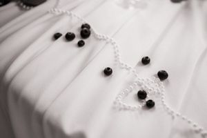 Close-up detail of white wedding dress fabric with decorative black button accents.