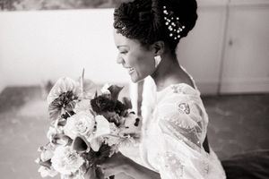 Black and white portrait of radiant bride holding classic white rose bouquet.
