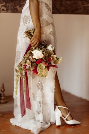White lace dress and floral bouquet details with elegant white heels.