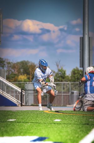 A lacrosse player in white uniform prepares to take a shot during a game.