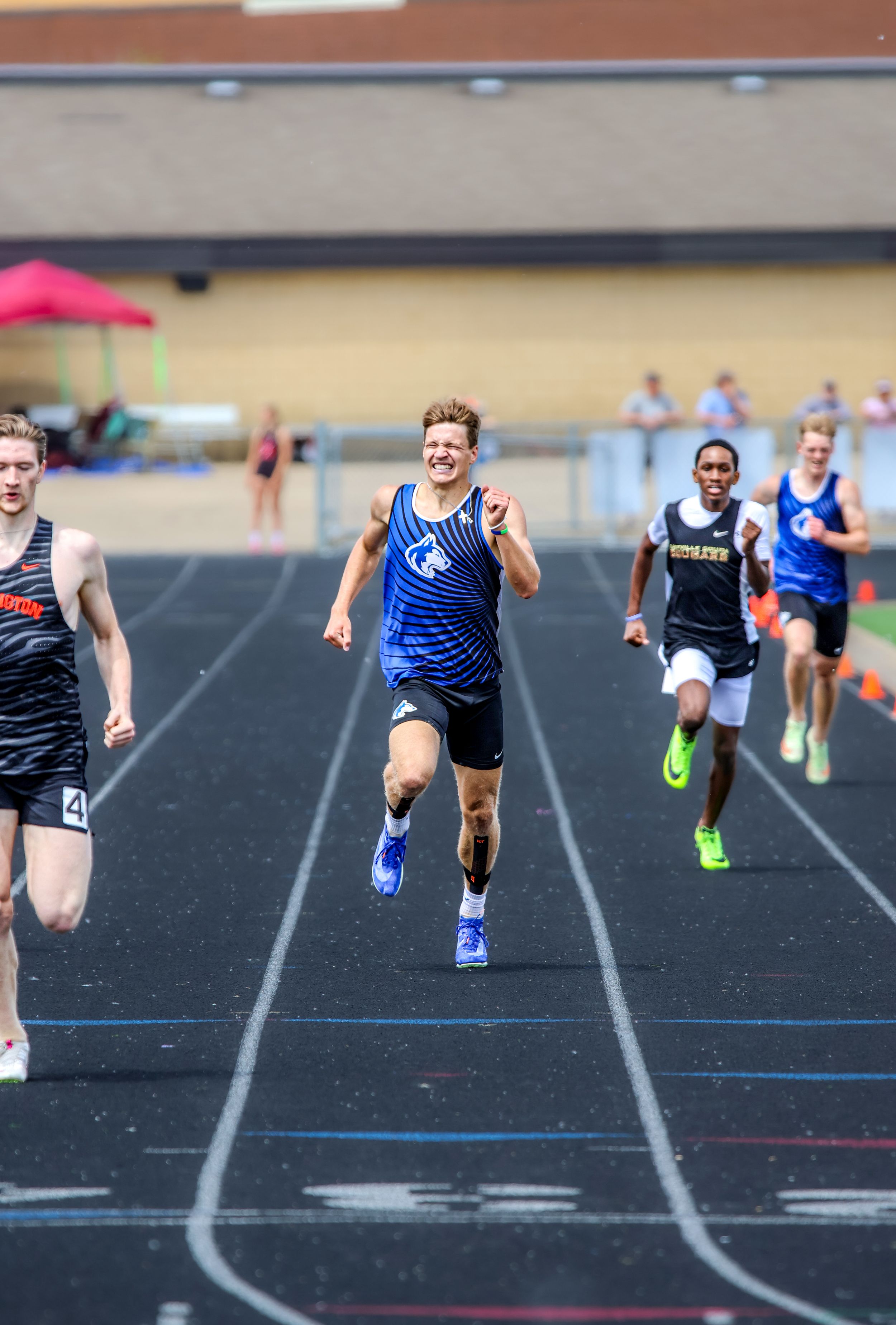 Sprinters competing in close race on outdoor track.