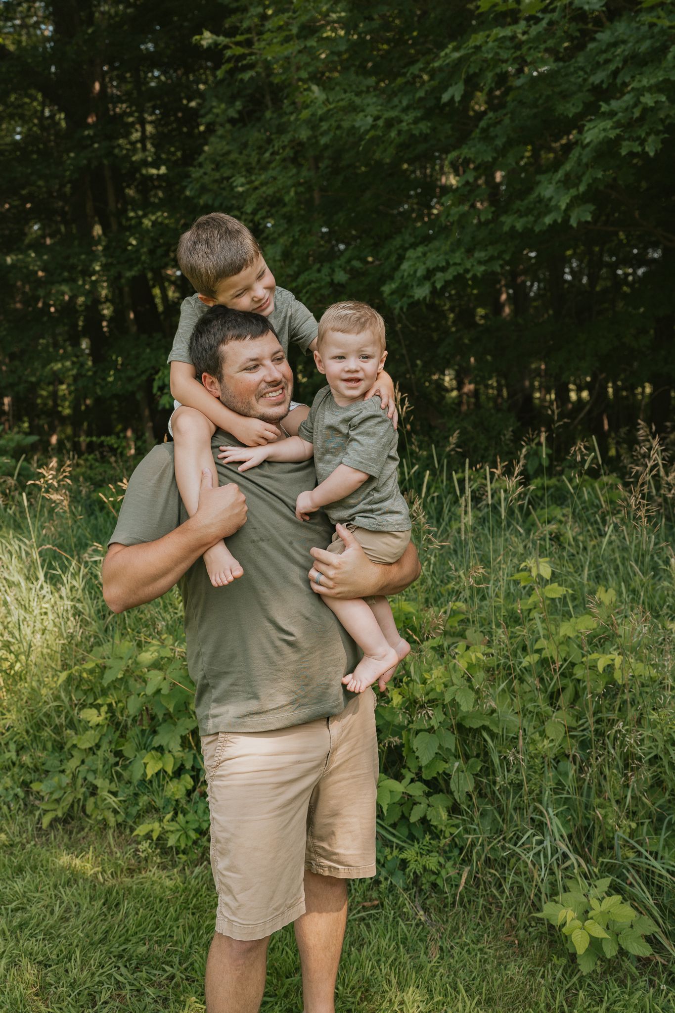 A joyful family moment outdoors with a parent and children playing together in a natural setting.