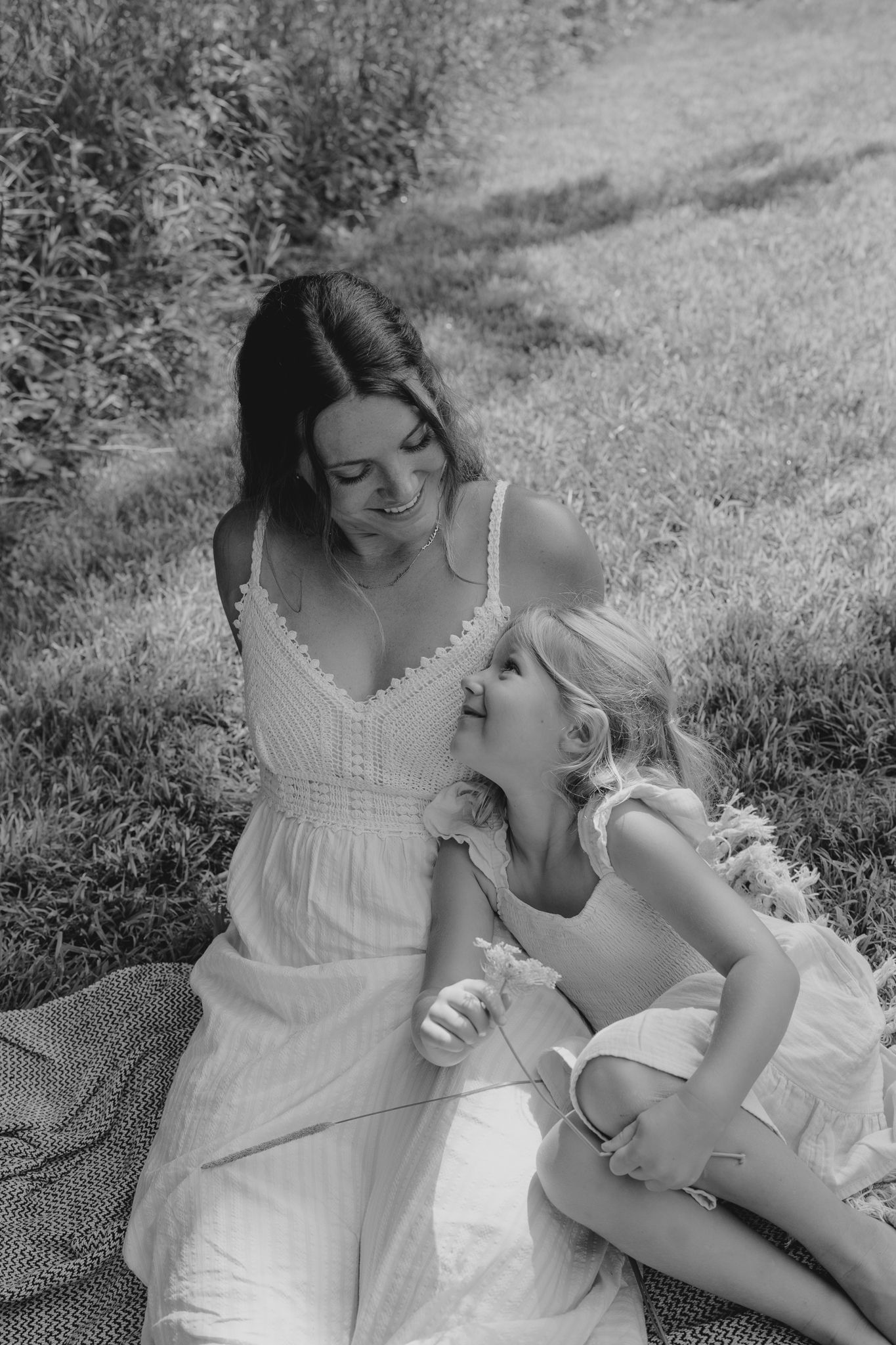 A tender black and white portrait of two people sharing a sweet moment while sitting on a blanket outdoors.
