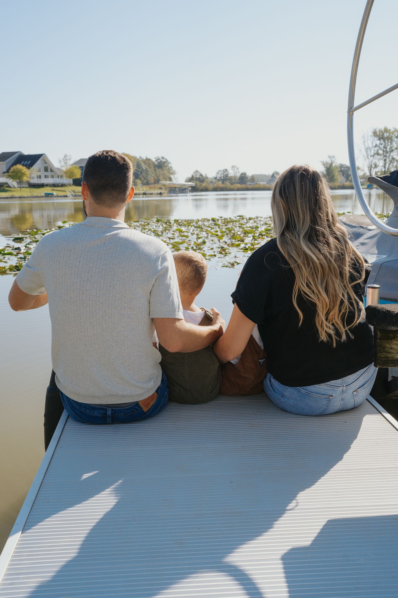 Group sitting together on white boat deck overlooking water and lily pads.