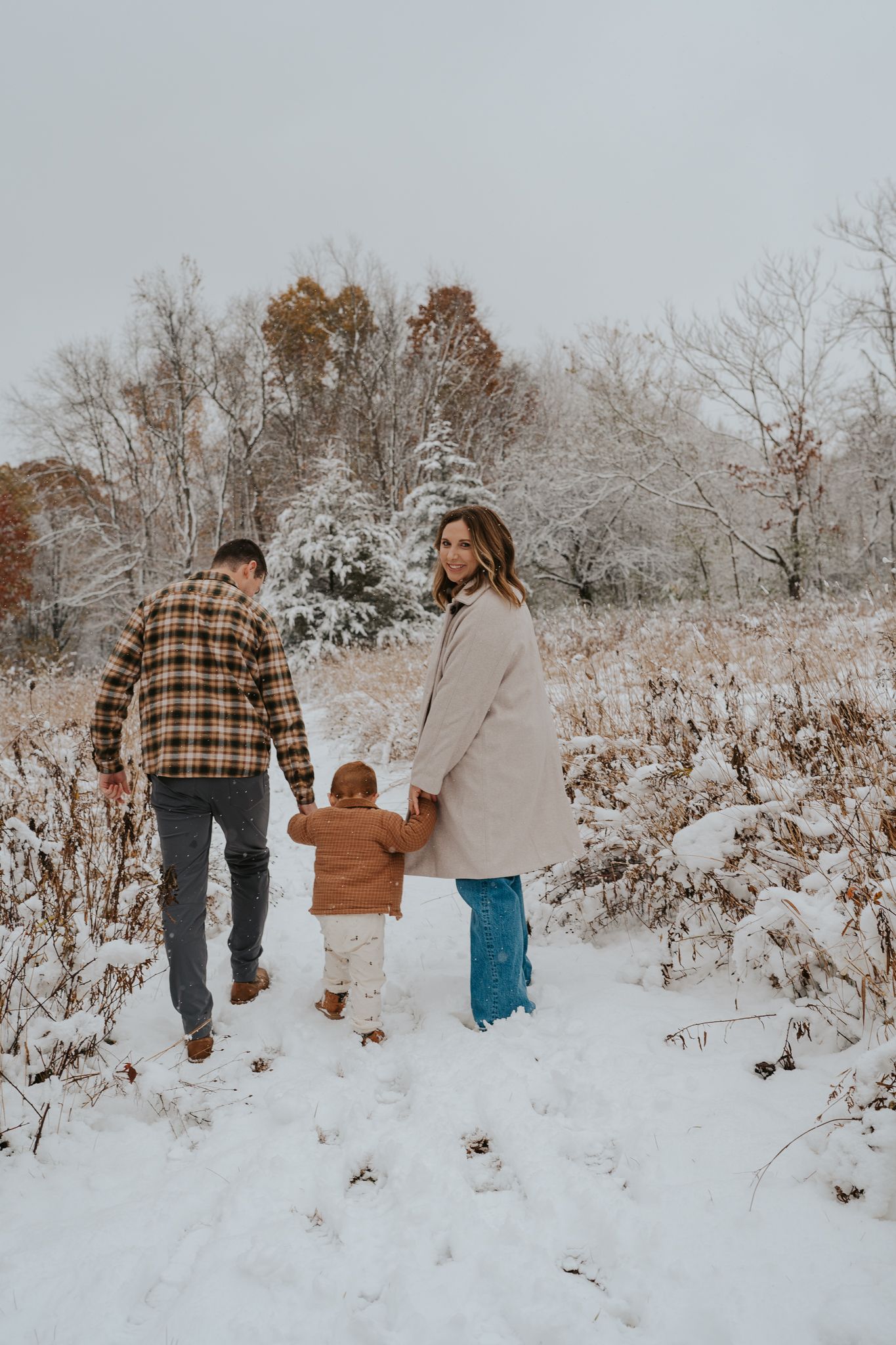 Family walking together through a snowy winter landscape holding hands on a cold day.