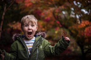 Happy child squealing with excitement and wearing a coat in autumnal surroundings