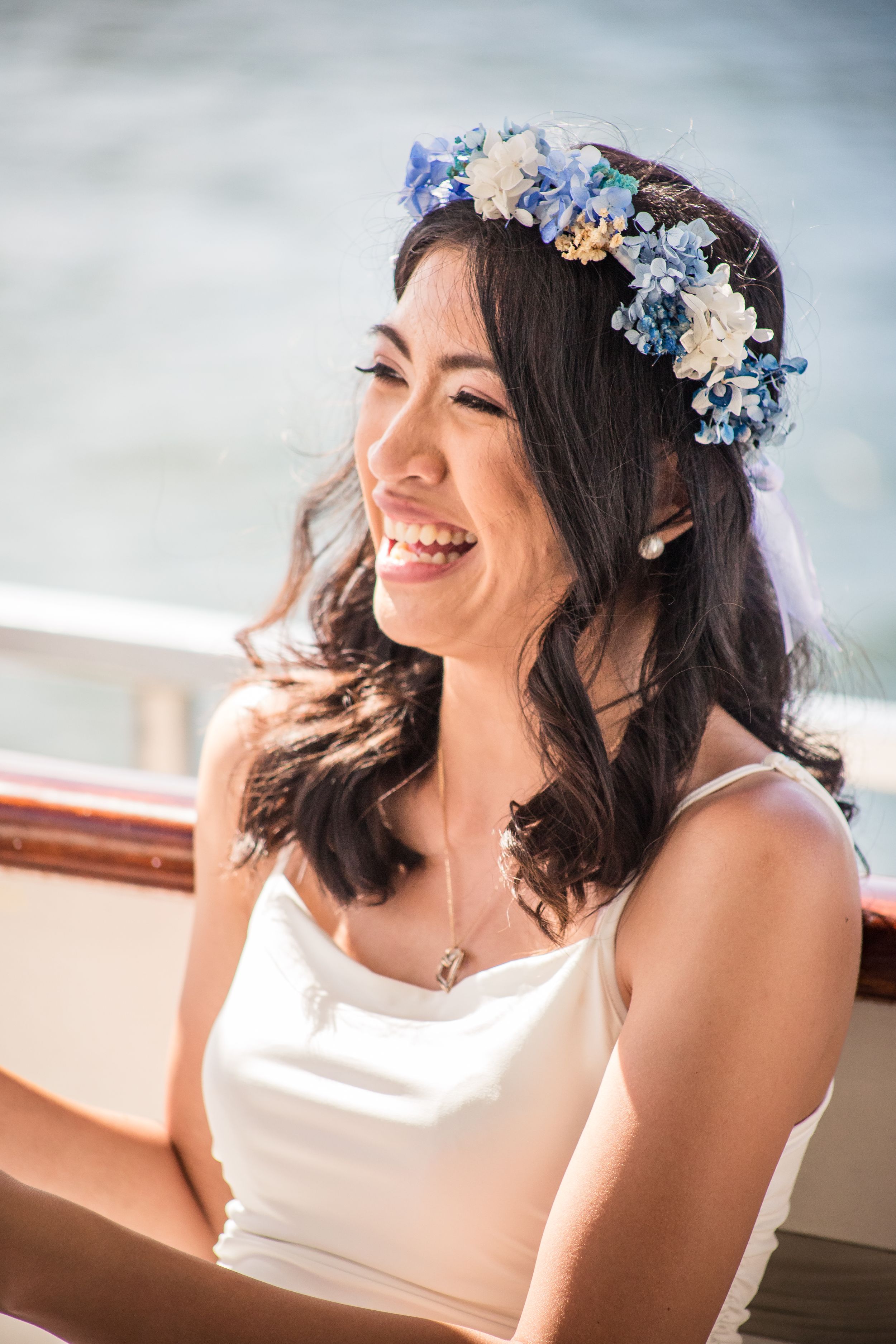 Happy bride wearing a blue and ivory flower crown on a boat in Sydney