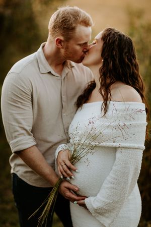 Romantic couple in white clothing share intimate moments against a natural outdoor backdrop.