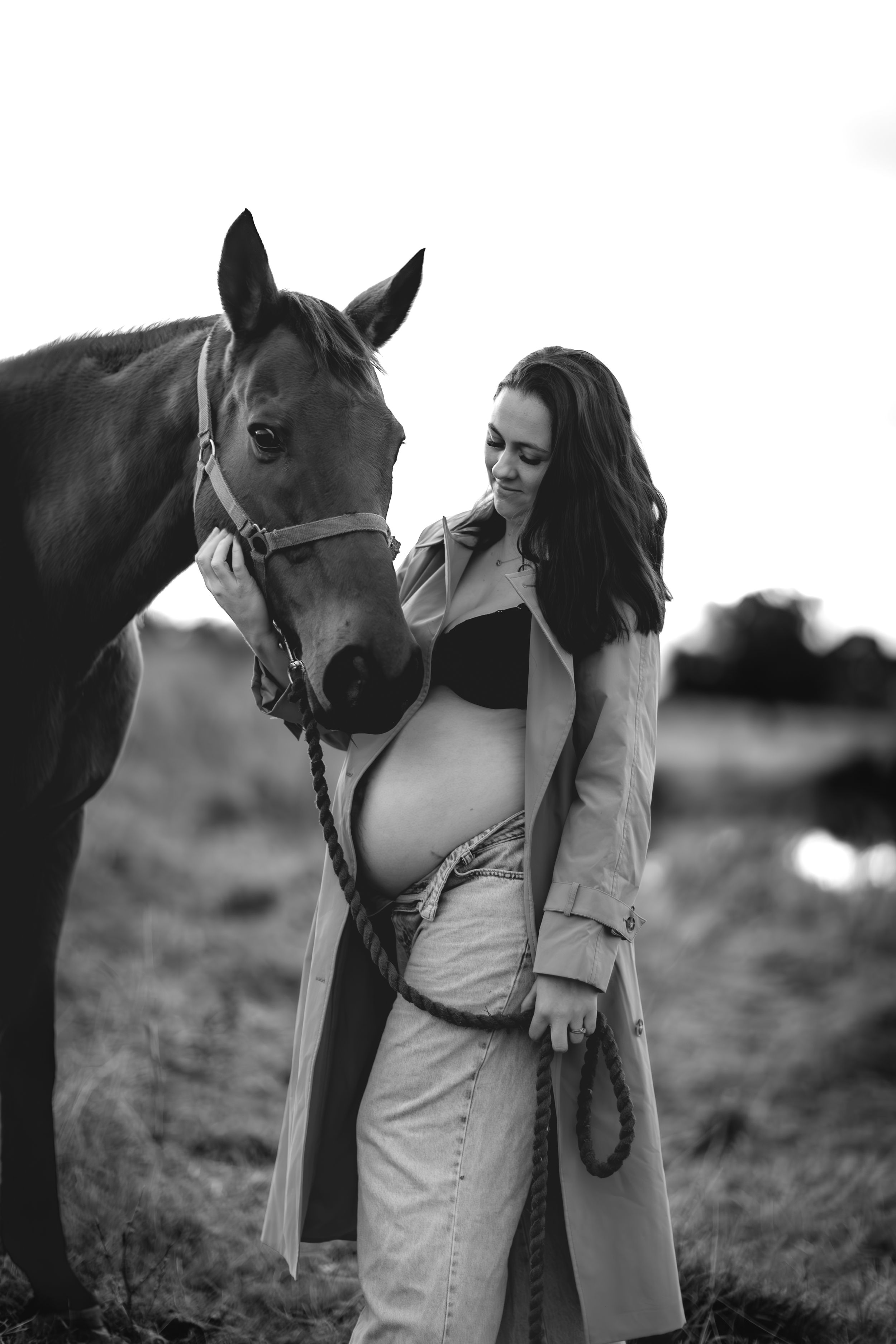 Black and white photos of a person bonding with horses in a field.