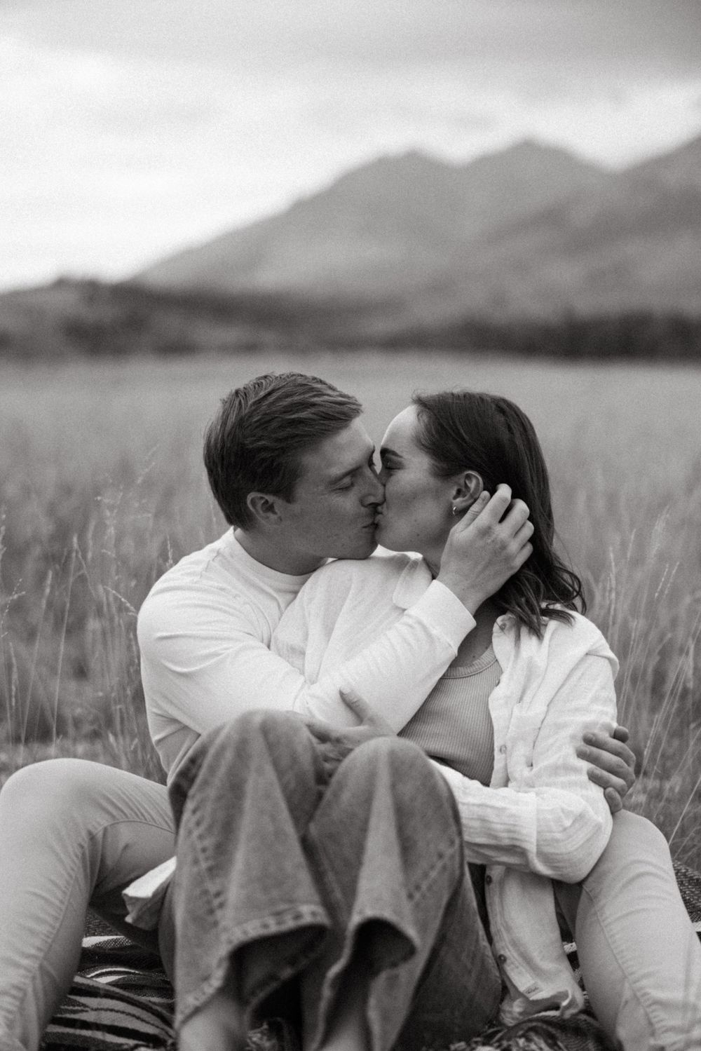 Romantic couple sharing intimate moments against a mountain backdrop.