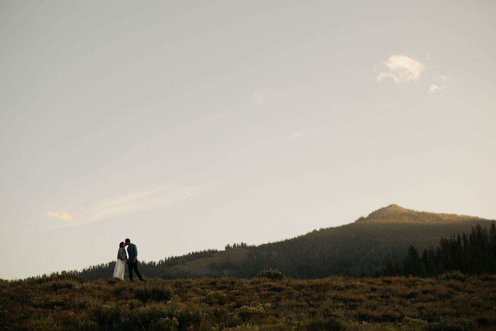 Silhouetted mountain landscape at dusk with rolling hills in the background.