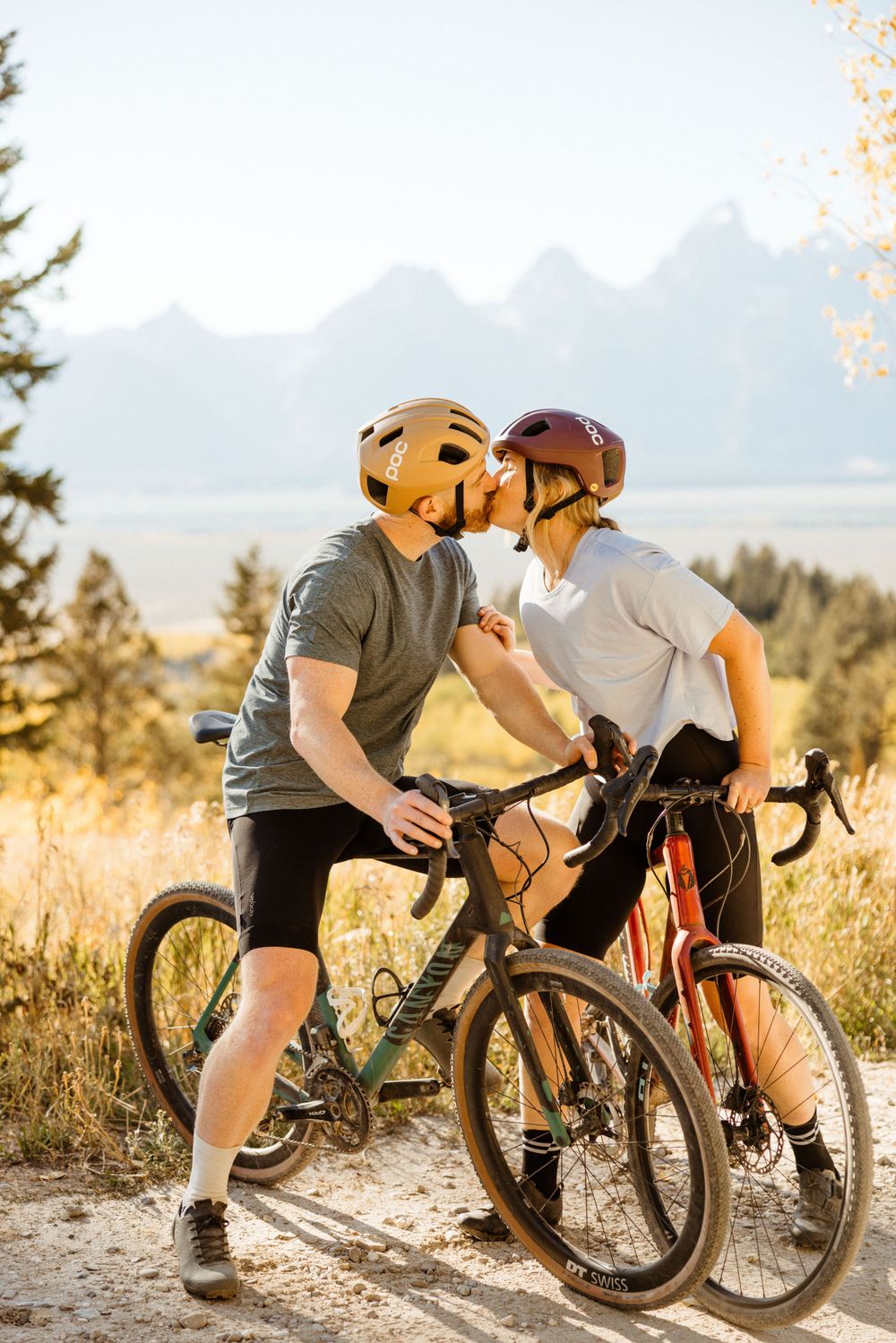 Two cyclists taking a break on a scenic mountain trail during golden hour.