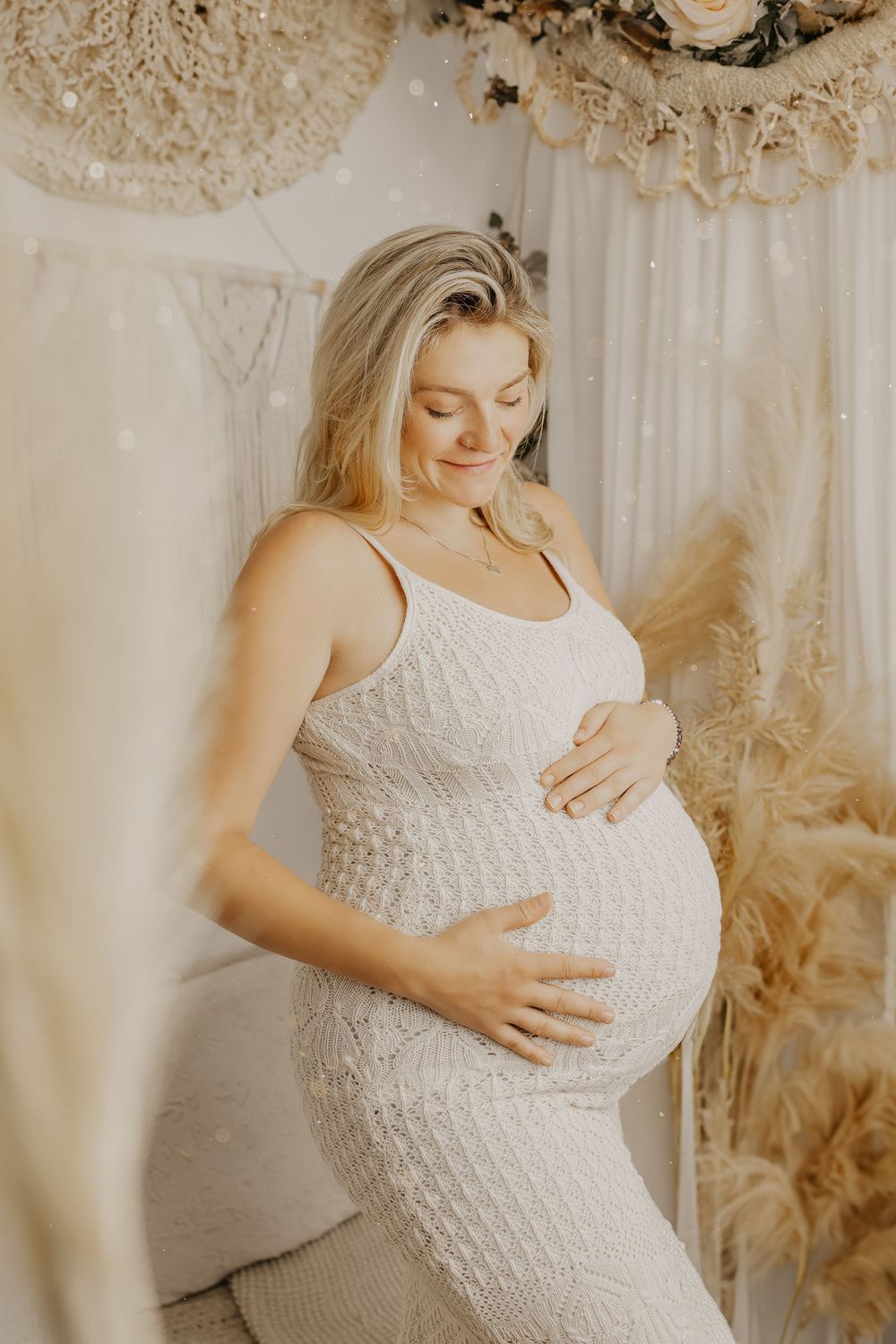 Elegant maternity portraits in textured white dress with dried floral arrangements.