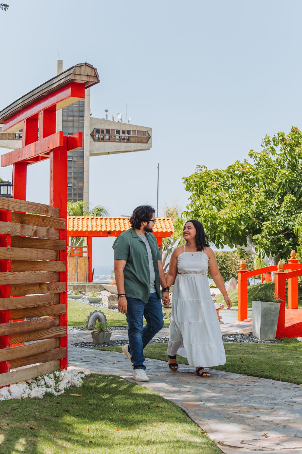 A couple takes a romantic stroll through a Japanese garden with red torii gates.