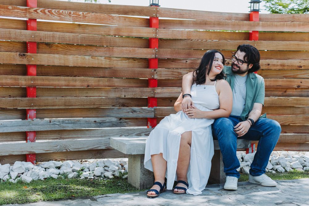 A couple sits intimately on wooden bench decorated with red lanterns.