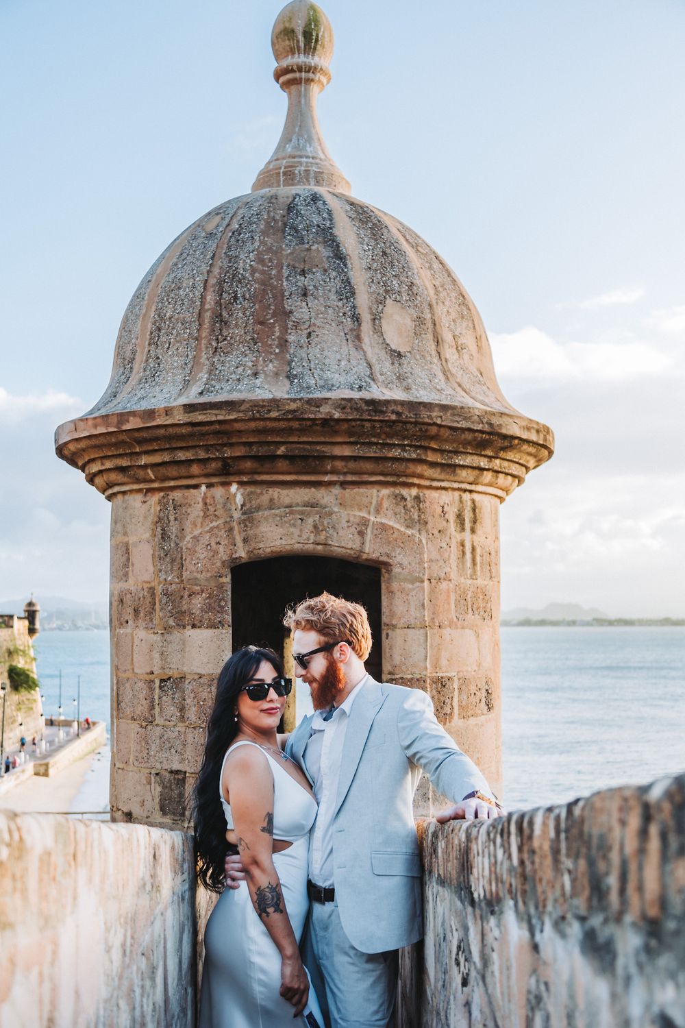 A couple shares an intimate moment in a historic stone watchtower by the sea.