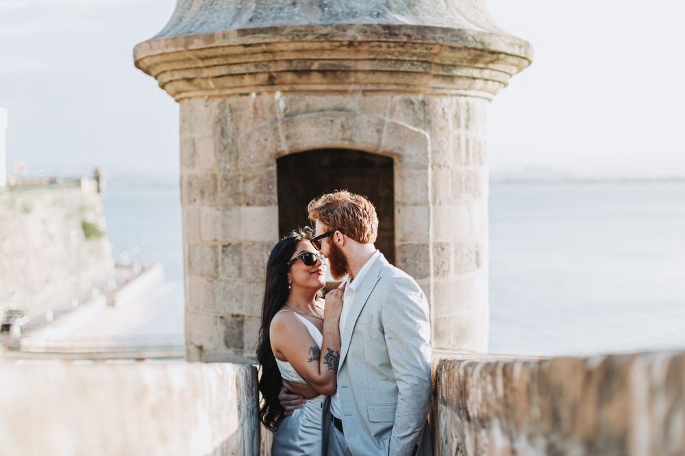 A couple embraces in a historic stone lookout tower overlooking the ocean.