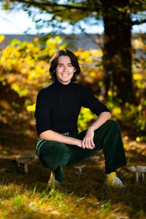 Autumn outdoor portrait with black turtleneck against yellow foliage background.