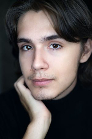Close-up dramatic portrait with soft lighting against dark background.