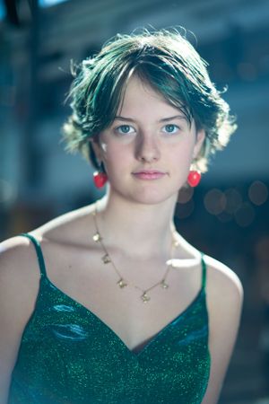 Portrait featuring emerald green dress, red earrings and delicate gold necklace.