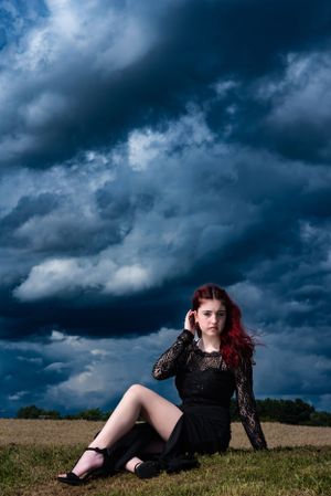 Moody outdoor portrait with dark stormy clouds and a black lace dress.