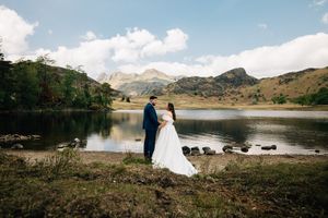 Wedding photography with scenic mountain lake and dramatic landscape backdrop.