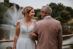 A couple shares a romantic moment in their wedding attire by a scenic lake on their special day.