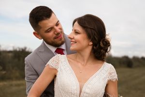 A romantic outdoor wedding photoshoot with a couple in formal attire sharing intimate moments in a natural setting.