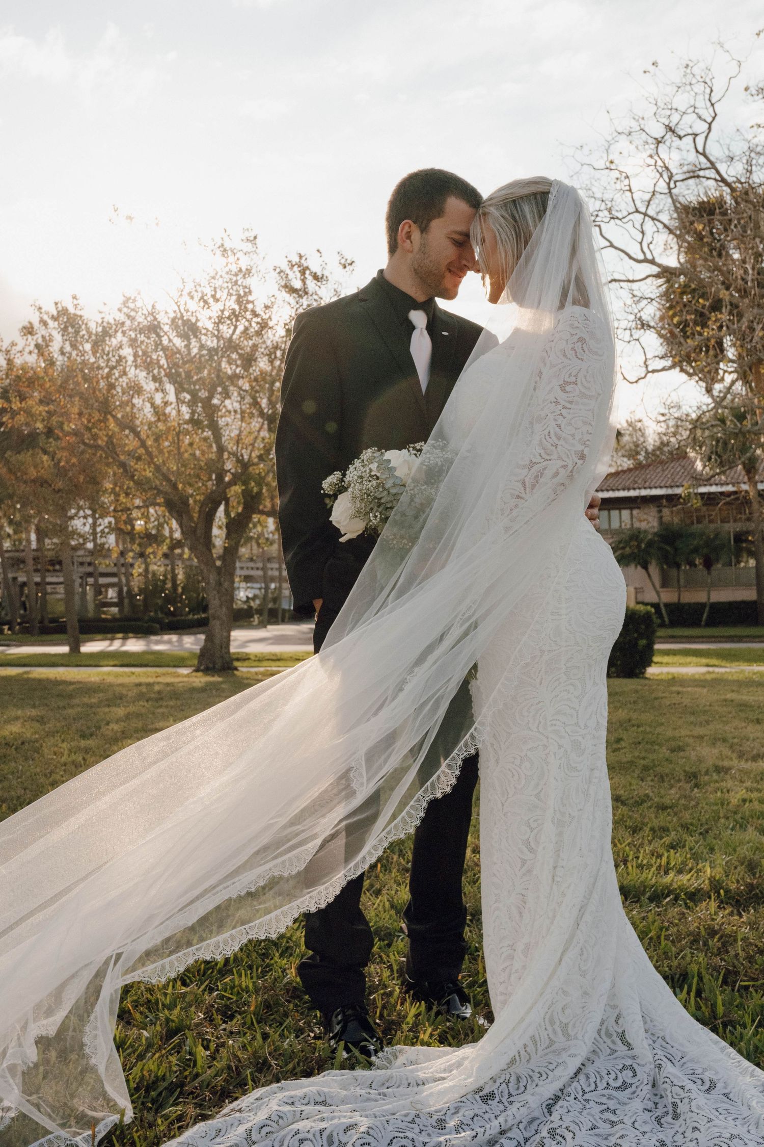 Dramatic wedding photos with a flowing veil catching the wind in an outdoor setting.