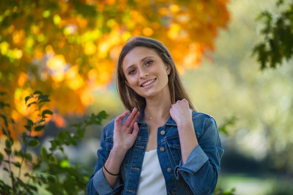 Senior girl in jean jacket among fall leaves, Faust Park fall senior photos St. Louis