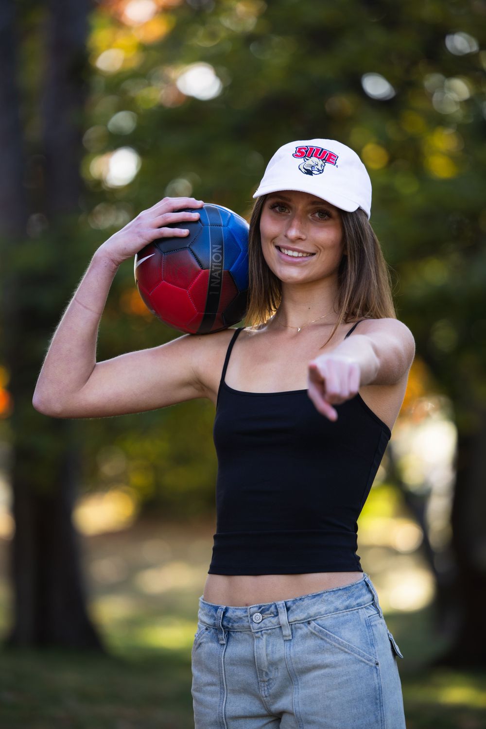 Senior girl in tank top with soccer ball in Faust Park fall senior photos St. Louis