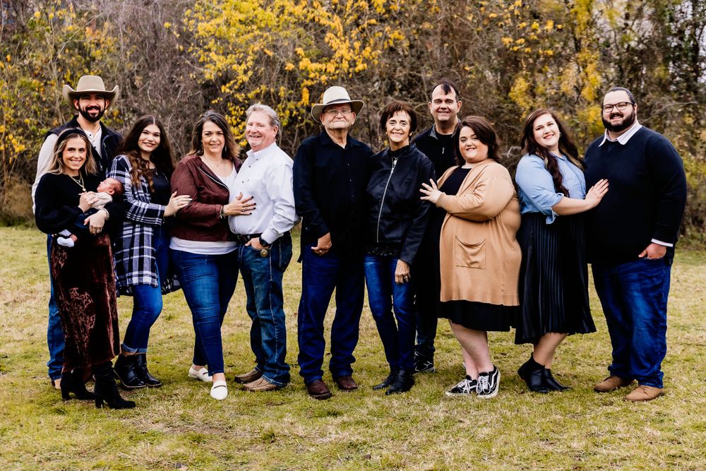 Large group poses together outdoors for a casual fall family photo.