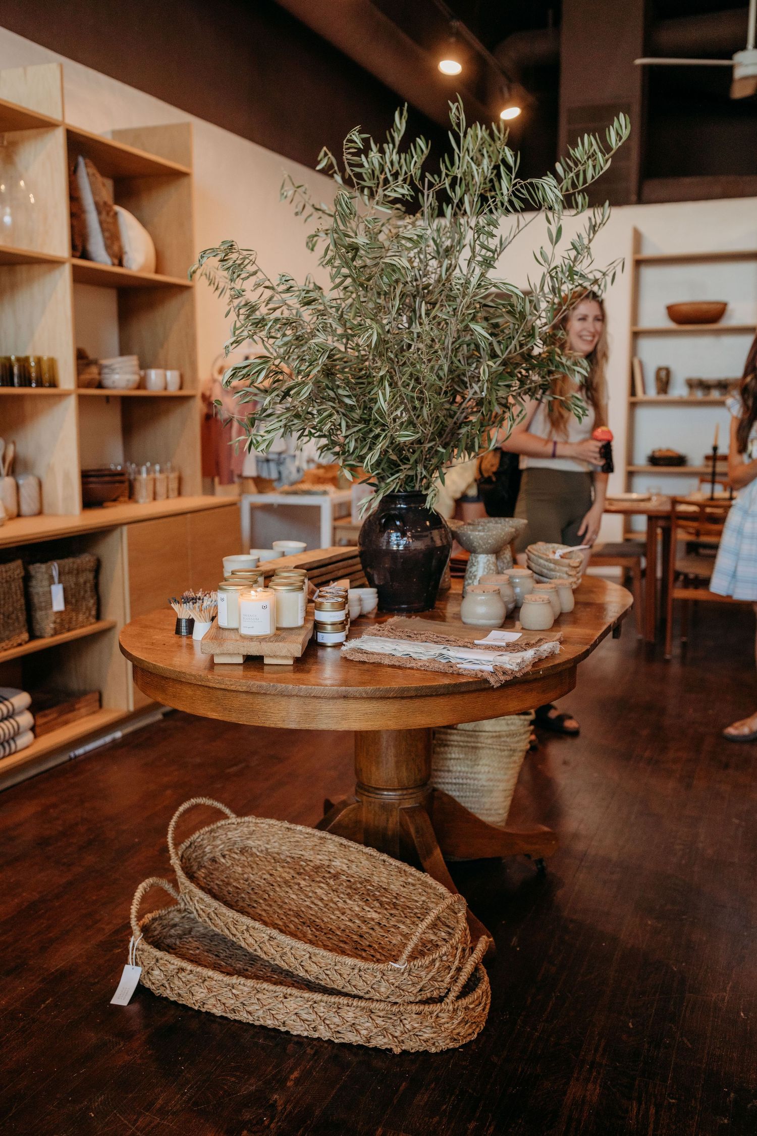 Rustic retail shop interior with olive branch centerpiece and wooden shelving.